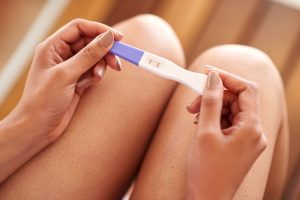 Cropped shot of a woman holding a pregnancy test that’s positive